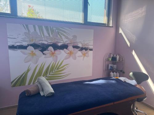 a bedroom with a blue bed with a flower mural on the wall at Alpine Lodge Bansko Apartments in Bansko