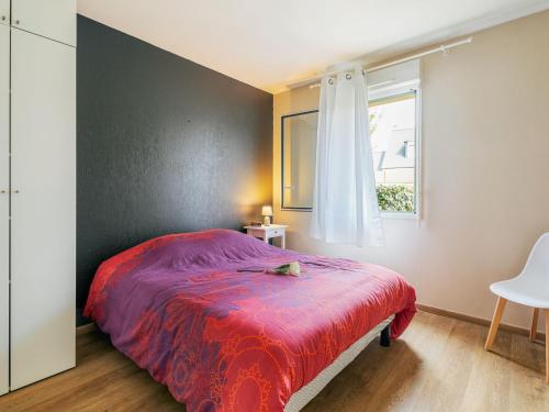 une chambre avec un lit avec une couverture rouge et une fenêtre dans l'établissement Apartment Le Moulin de Rose by Interhome, à Dinard