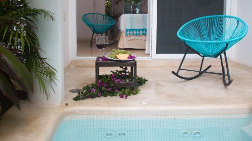 a swimming pool with two chairs and a table with flowers at LiveTulum in Tulum