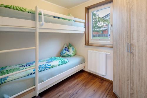 a small bedroom with bunk beds and a window at Ferienhäuser Hainichhöhe in Hörselberg-Hainich