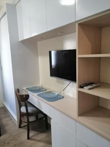 a desk with a television and a chair in a room at Homey Staycation in Silang Cavite! Fullerton Suites Puting Kahoy - near CKS, AUP, PNPA, in Puting Kahoy