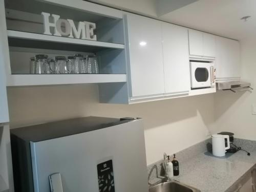 a kitchen with white cabinets and a sink and a microwave at Homey Staycation in Silang Cavite! Fullerton Suites Puting Kahoy - near CKS, AUP, PNPA, in Puting Kahoy