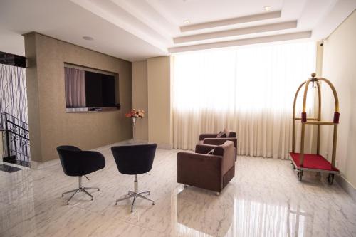 a living room with chairs and a couch and a television at Padom Business Hotel in Bragança Paulista