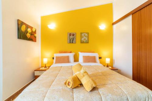 a bedroom with a large bed with yellow walls at B&B Rita E Renzo in Riola Sardo
