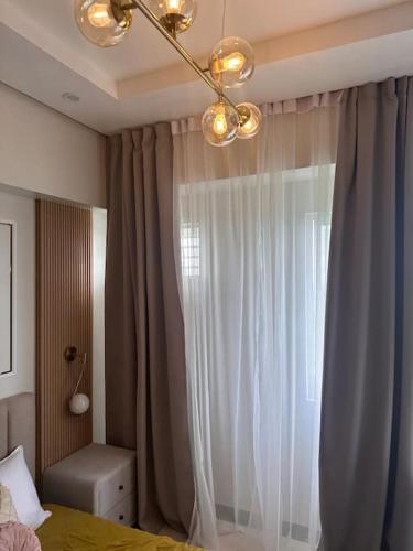 a bedroom with a bed and a window with curtains at Haiya's Staycation Aesthetic & Cozy in Tagaytay in Biluso