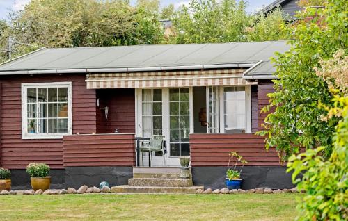 a small red house with a chair on the porch at 2 Bedroom Beach Front Home In Rude in Rude