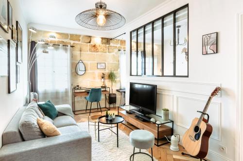 un salon avec un canapé et une guitare dans l'établissement Magnifique Appartement pour 2 en Centre-Ville, à Bordeaux