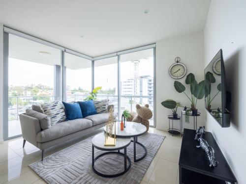 a living room with a couch and a table at Modern 3BR Riverside APT w Parking near Shops and Park in Brisbane
