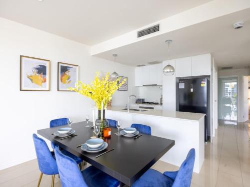 a kitchen and dining room with a black table and blue chairs at Modern 3BR Riverside APT w Parking near Shops and Park in Brisbane