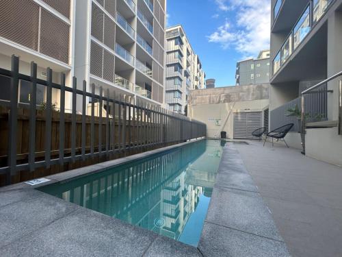 a swimming pool with a chair next to a building at Modern 3BR Riverside APT w Parking near Shops and Park in Brisbane