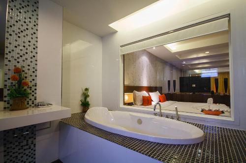 La salle de bains est pourvue d'une baignoire et d'un grand miroir. dans l'établissement Platinum Hotel and Apartments, à Patong Beach