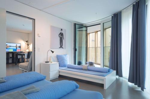 a living room with two blue beds and a window at HITrental Allmend Comfort Apartments in Luzern