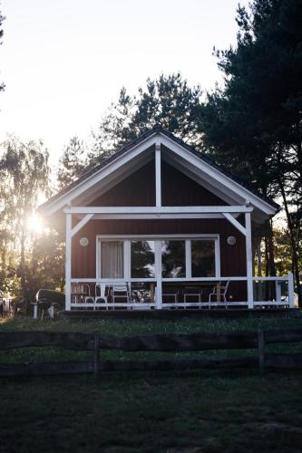 a house with a porch with chairs in front of it at Tiny Houses & Schwedenhäuser Ahoi Camp Canow in Wustrow