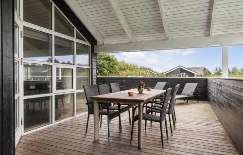 a wooden table and chairs on a deck at Awesome Home In Hemmet With Sauna in Hemmet