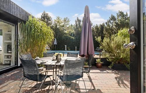 a patio with a table and chairs and an umbrella at Amazing Home In Sjællands Odde in Yderby