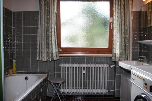 a bathroom with a tub and a sink and a window at Haus Auzinger in Schönau am Königssee