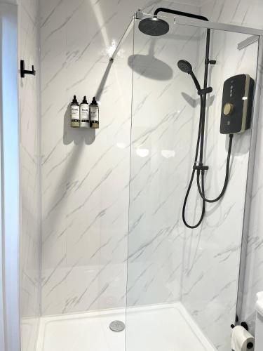 a bathroom with a shower with white marble at Dinmont Cottage in Dalston
