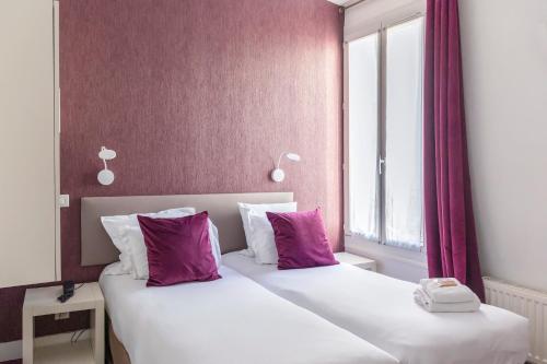 two beds in a hotel room with purple walls at Porte de Versailles Hotel in Paris