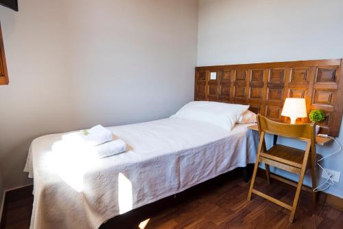 a small bedroom with a bed and a chair at Paratene Ostatu Habitaciones in Erandio