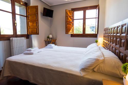 a bedroom with a large white bed with two windows at Paratene Ostatu Habitaciones in Erandio