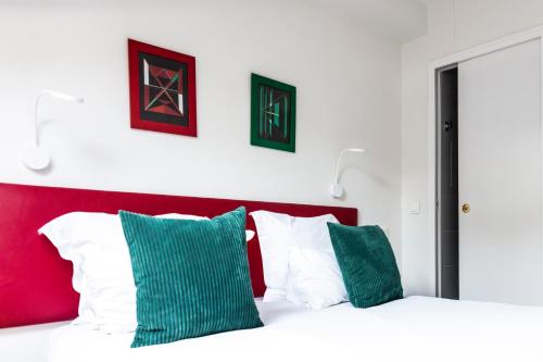 a bedroom with a red and white bed with green pillows at Porte de Versailles Hotel in Paris