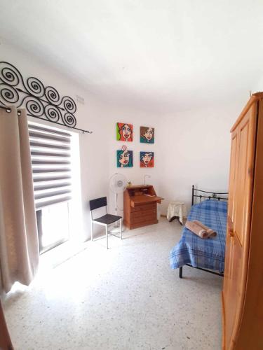 a bedroom with a bed and a desk and a window at Swatar Cosy Apartment in Is-Swatar