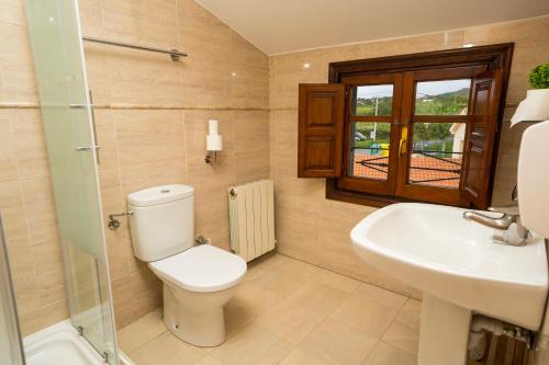 a bathroom with a toilet and a sink at Paratene Ostatu Habitaciones in Erandio