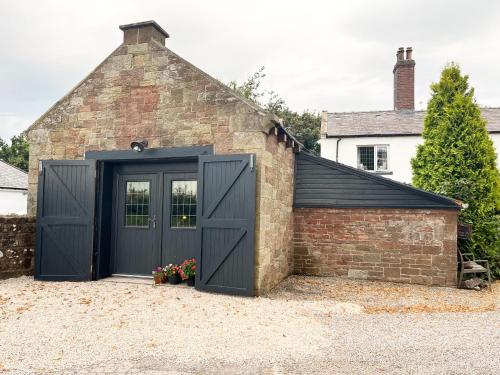 a garage with black doors and a brick building at Dinmont Cottage in Dalston