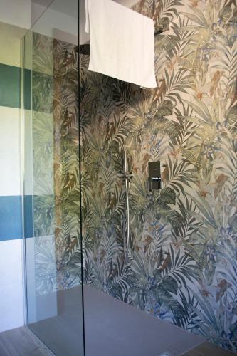 a bathroom with a glass shower with a wallpaper at Casa di Nina in Oleggio Castello