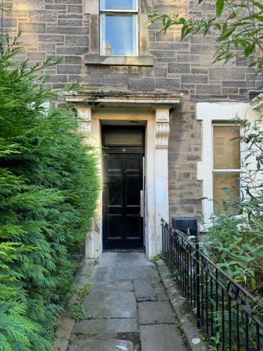 a black door to a brick building at Central Room In Historic Tenement Shared Apartment Near Old Town in Edinburgh