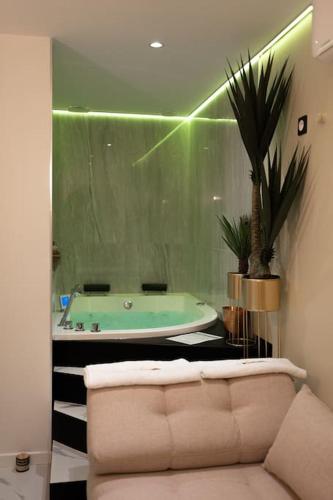 La salle de bains est pourvue d'une baignoire verte et d'un canapé. dans l'établissement Love room Dubaï & Balnéo, à Saint-Rambert-dʼAlbon