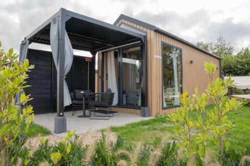 a small house with a black roof at Luxe tinyhouse 2 op minicamping in waarde in Waarde