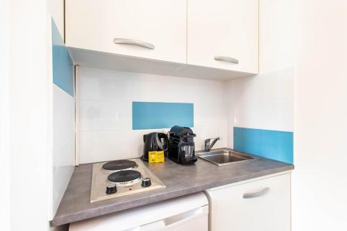 Il comprend une petite cuisine équipée d'une cuisinière et d'un évier. dans l'établissement Magnificent studio - 2P - Moulin Rouge, à Paris