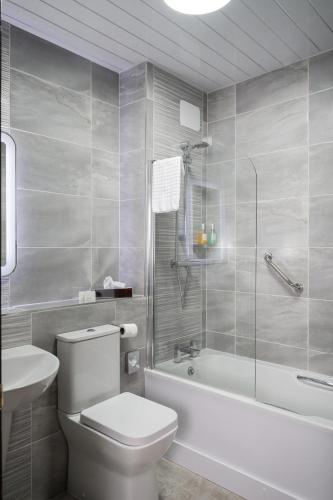 a bathroom with a toilet and a tub and a sink at Jackson's Hotel & Leisure Centre in Ballybofey