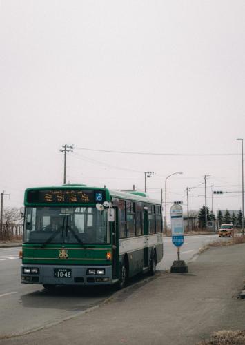 a green and white bus driving down a street at JaM in Noboribetsu