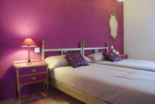 a bedroom with two beds and a purple wall at Casa rural Olivar de Albarizas in Fernancaballero