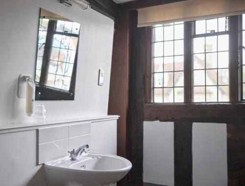 a bathroom with a sink and a mirror and a window at Bull Hotel by Greene King Inns in Long Melford