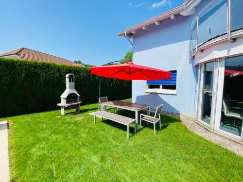 a patio with a table and a red umbrella at Villa with Pool - Leon's Holiday Homes in Dottikon