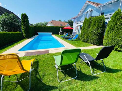a group of chairs sitting in the grass near a swimming pool at Villa with Pool - Leon's Holiday Homes in Dottikon