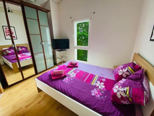 a bedroom with a bed with purple sheets and a mirror at Villa with Pool - Leon's Holiday Homes in Dottikon