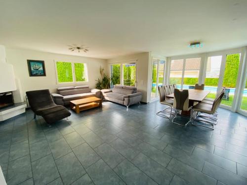 a large living room with a table and chairs at Villa with Pool - Leon's Holiday Homes in Dottikon