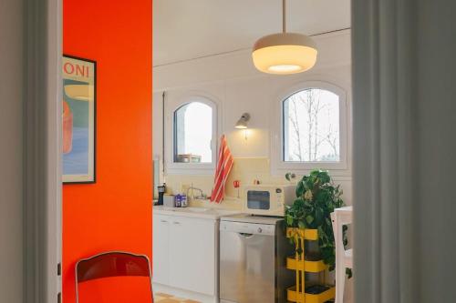 une cuisine avec un mur d'accent orange et un comptoir dans l'établissement Maison de montagne, à Passy