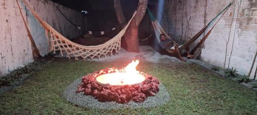 a man laying in a hammock next to a fire at Vila dos Bangalôs in Barreirinhas