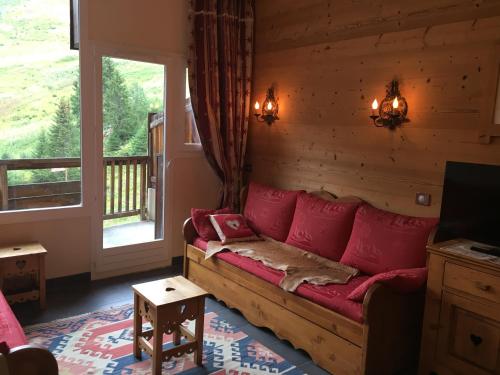a living room with a red couch and a window at Le Mazot - Avoriaz- séjours du dimanche au dimanche in Avoriaz