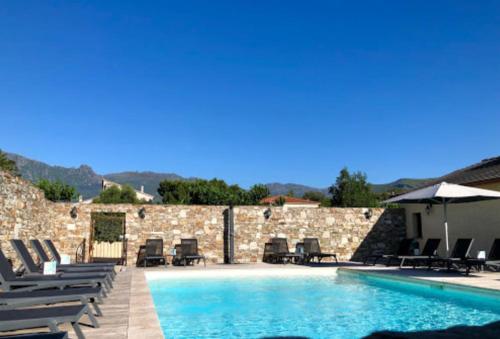 una piscina con sedie e ombrelloni di Bel appartement avec piscine Cap Corse- Sisco a Marine de Sisco
