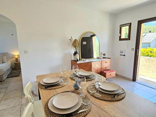 una sala da pranzo con un tavolo con piatti e bicchieri da vino di Bel appartement avec piscine Cap Corse- Sisco a Marine de Sisco
