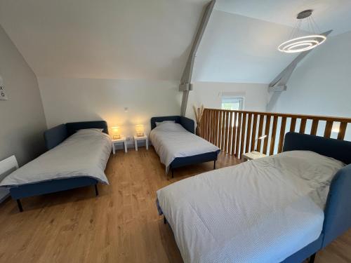 a room with two beds and a wooden floor at Belle maison au calme avec parking in Bretteville-sur-Odon