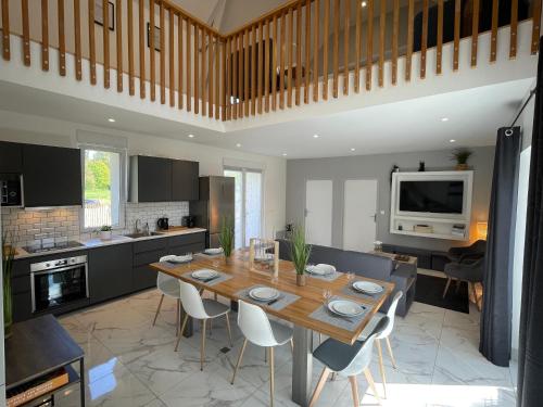 une cuisine et une salle à manger avec une table et des chaises en bois dans l'établissement Belle maison au calme avec parking, à Bretteville-sur-Odon