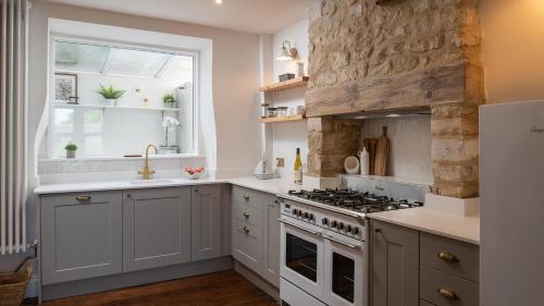 a kitchen with a stove and a window at Lucknow Cottage in Stroud