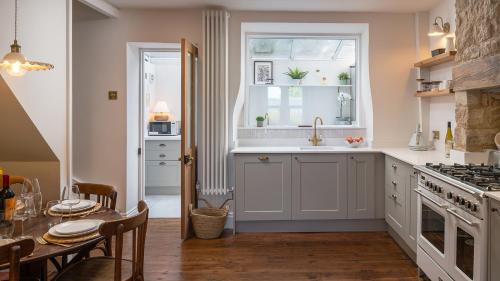 a kitchen with a sink and a window and a table at Lucknow Cottage in Stroud
